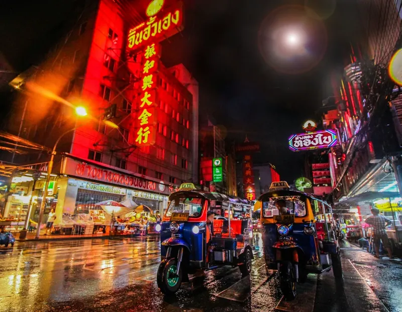 Neon signs and tuk-tuks on a rainy Bangkok night
