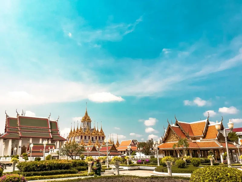 Golden temple roofs under a bright Bangkok sky